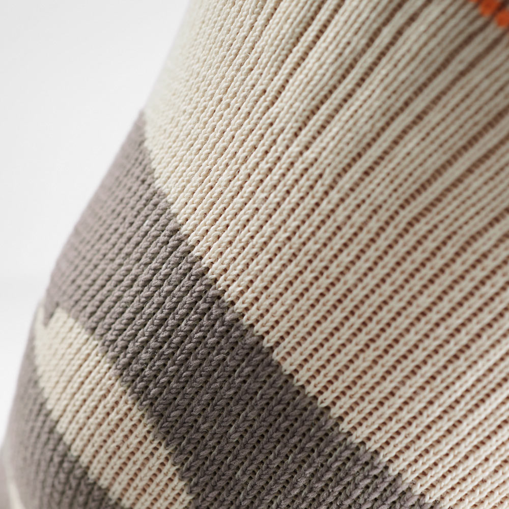Close-up of the sand-colored knee support with elastic knit pattern. The fine texture ensures stability during hiking, running, and other outdoor sports.