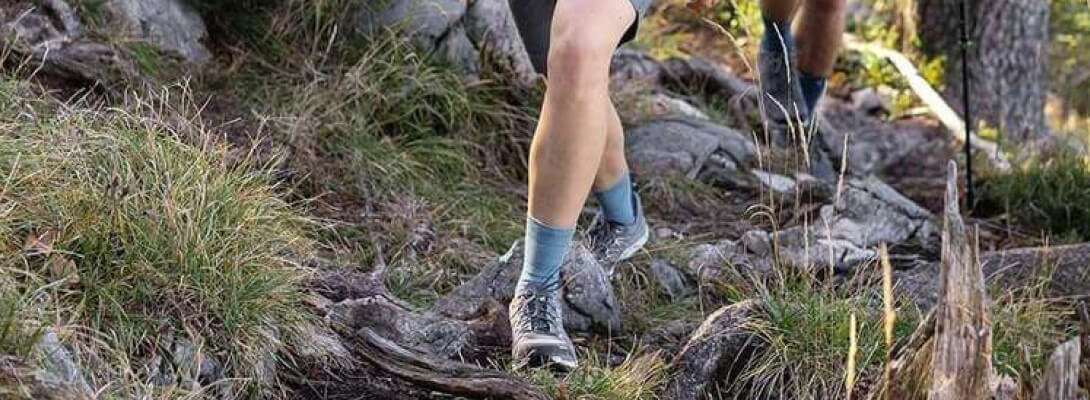 Medium-length merino hiking socks while hiking in the forest Wandering woman on a stony surface wears medium -length hiking socks