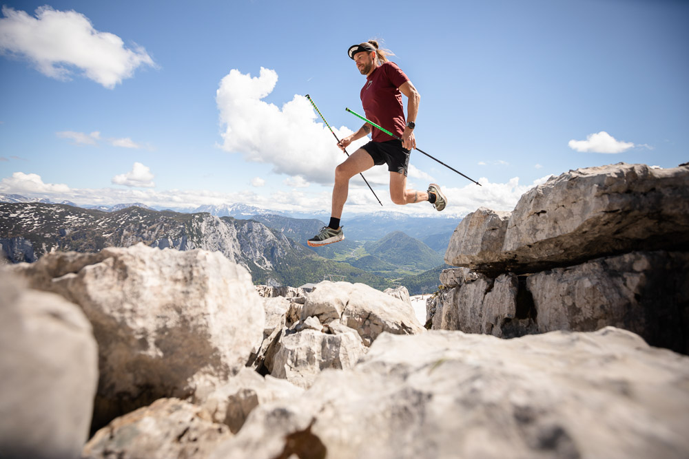Lord Jens Kramer trail running with poles and jumping across rocks in the high mountains