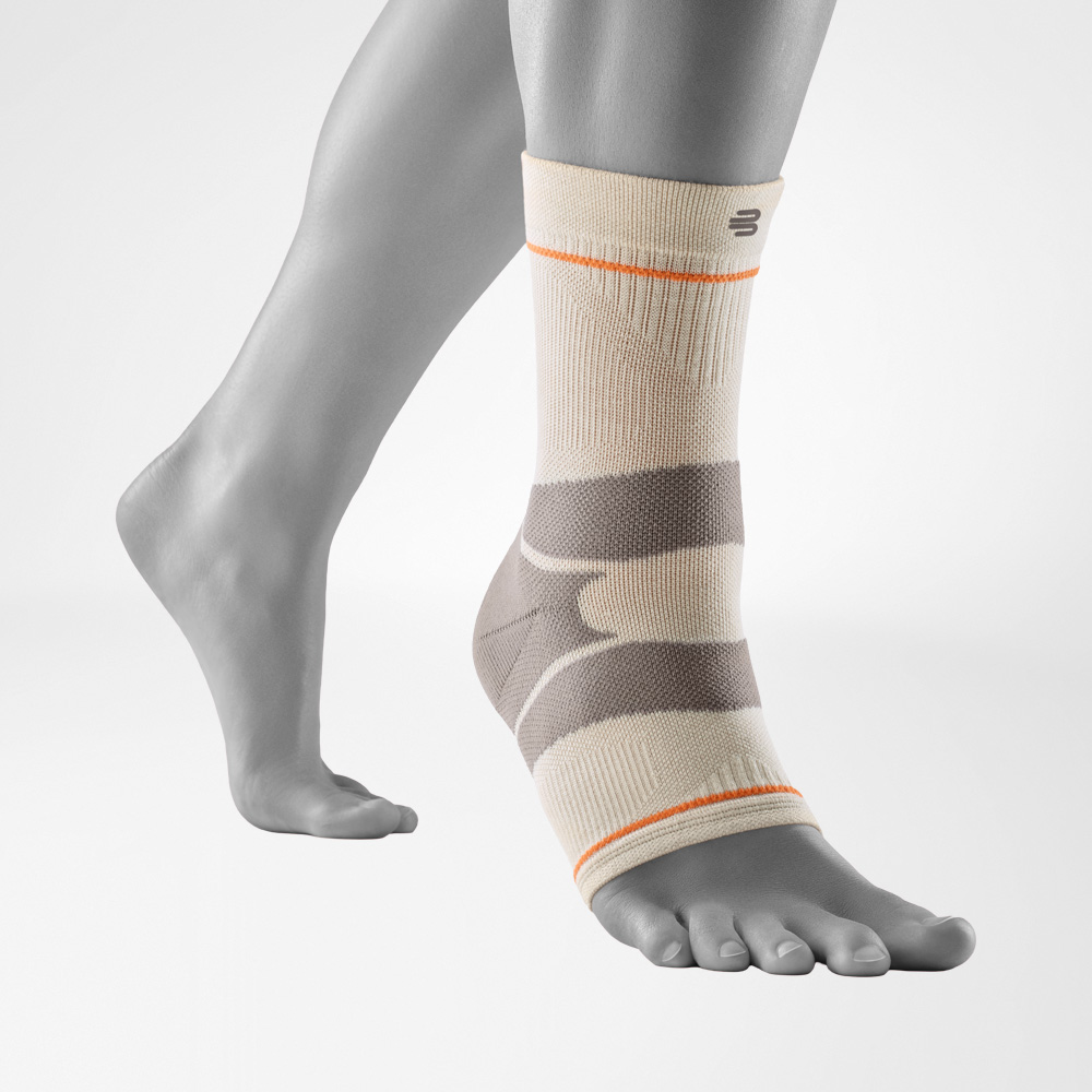 Outdoor Compression Ankle Support in sandstone color, worn on the right foot against a neutral grey background. The ankle support wraps the foot and ankle with zoned compression
