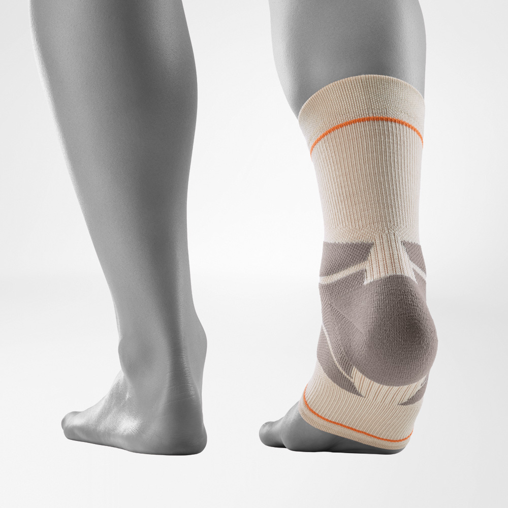 Outdoor Compression Ankle Support in sandstone color shown from the rear view, worn on the right foot against a grey background. The ankle support highlights anatomically shaped compression zones around the heel and Achilles area